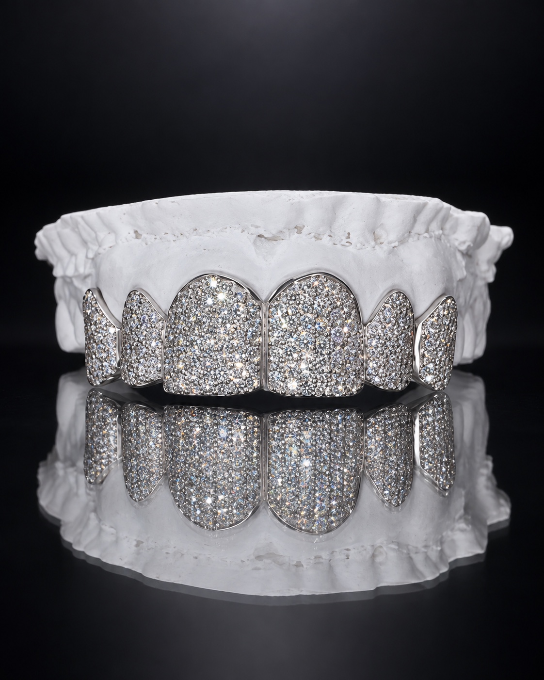 Fully iced silver top grillz displayed on a reflective black surface